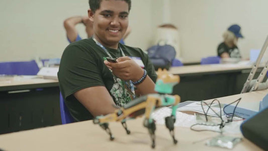 high school student smiling while playing with robot bittle robot dog